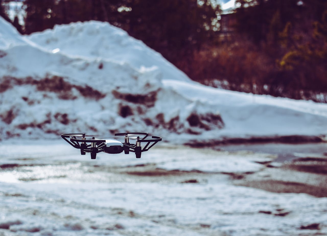 A drone hovering over a snowy terrain with blurred winter background.