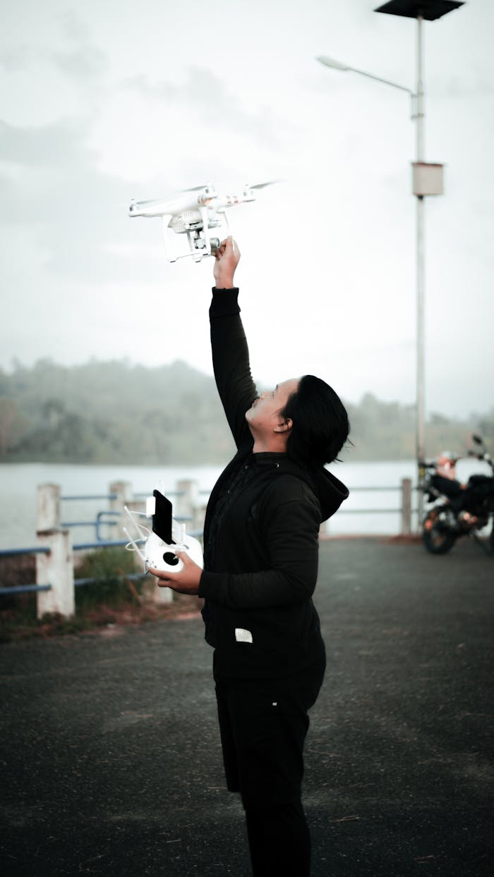 The Art of Drawing Readers In: Your attractive post title goes here Young adult male pilot controlling a drone outdoors near a scenic water view.