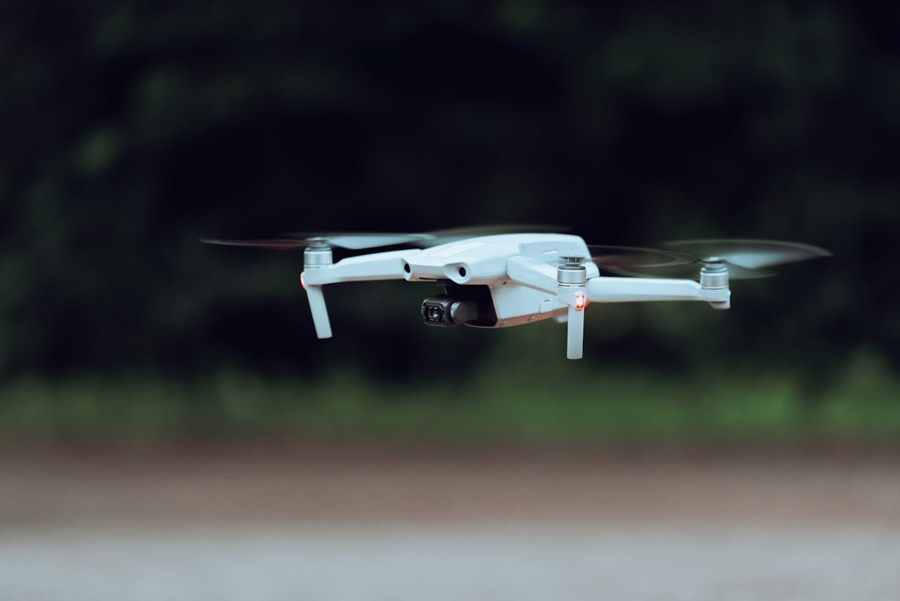 A close-up shot of a white drone flying outdoors in a natural setting.